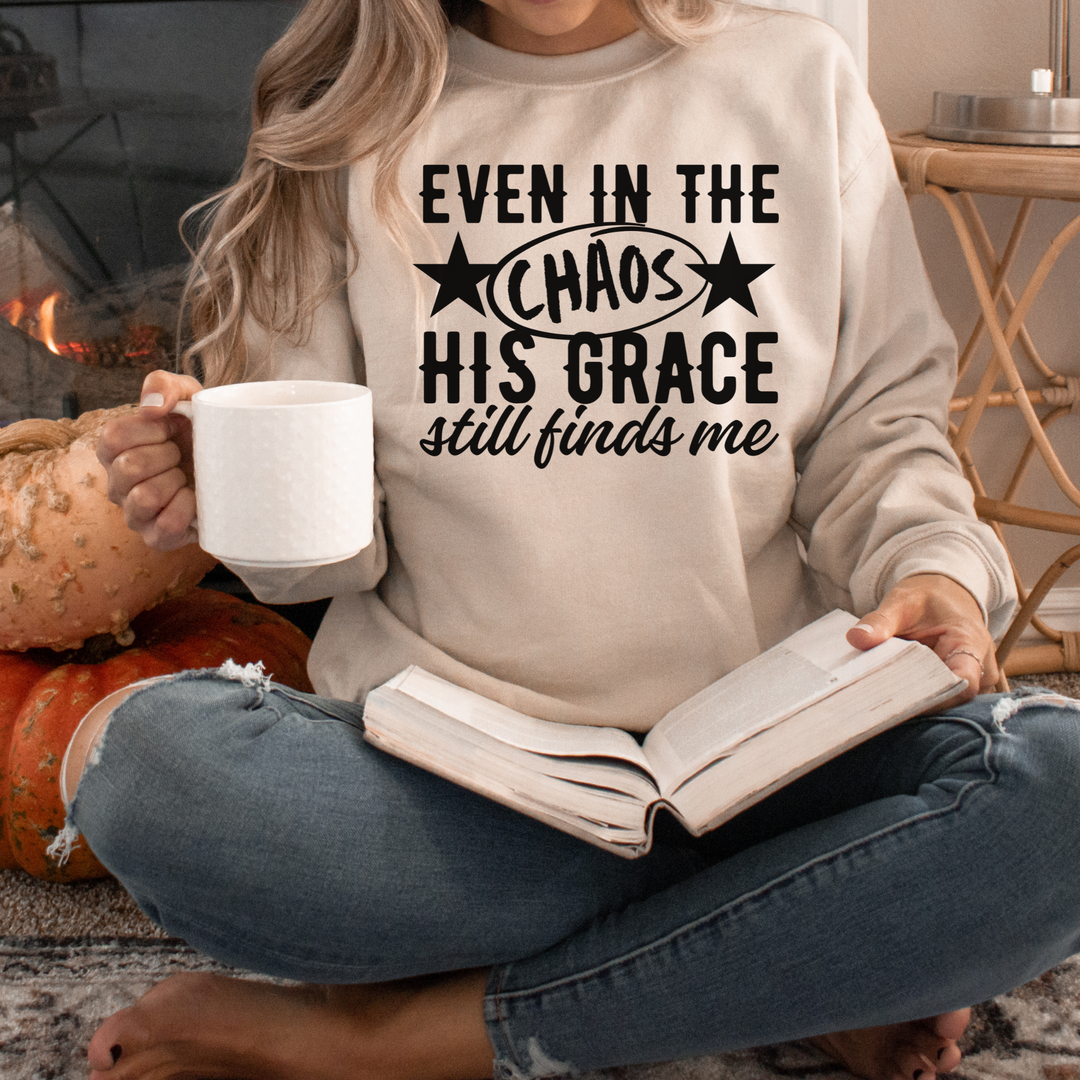 Person wearing a sweatshirt with a motivational quote, holding a mug and an open book, sitting by a fireplace.