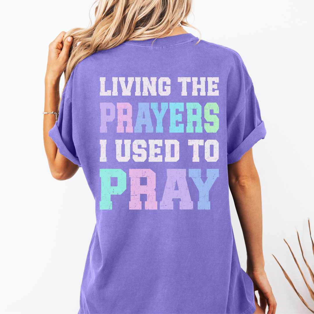 Purple t-shirt with colorful text on the back worn by a person, against a plain background.