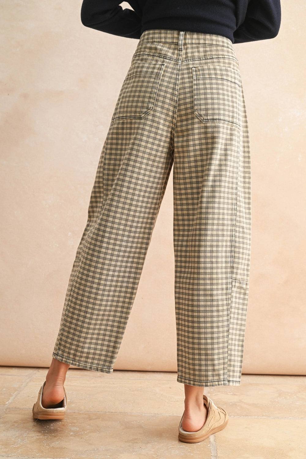 Person wearing plaid pants on a beige background