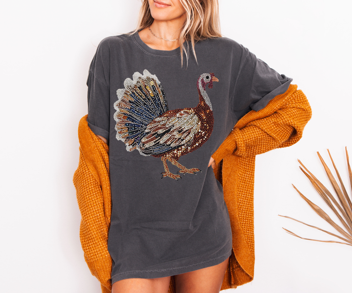 Person wearing a gray sweatshirt with a turkey design and an orange cardigan on a white background