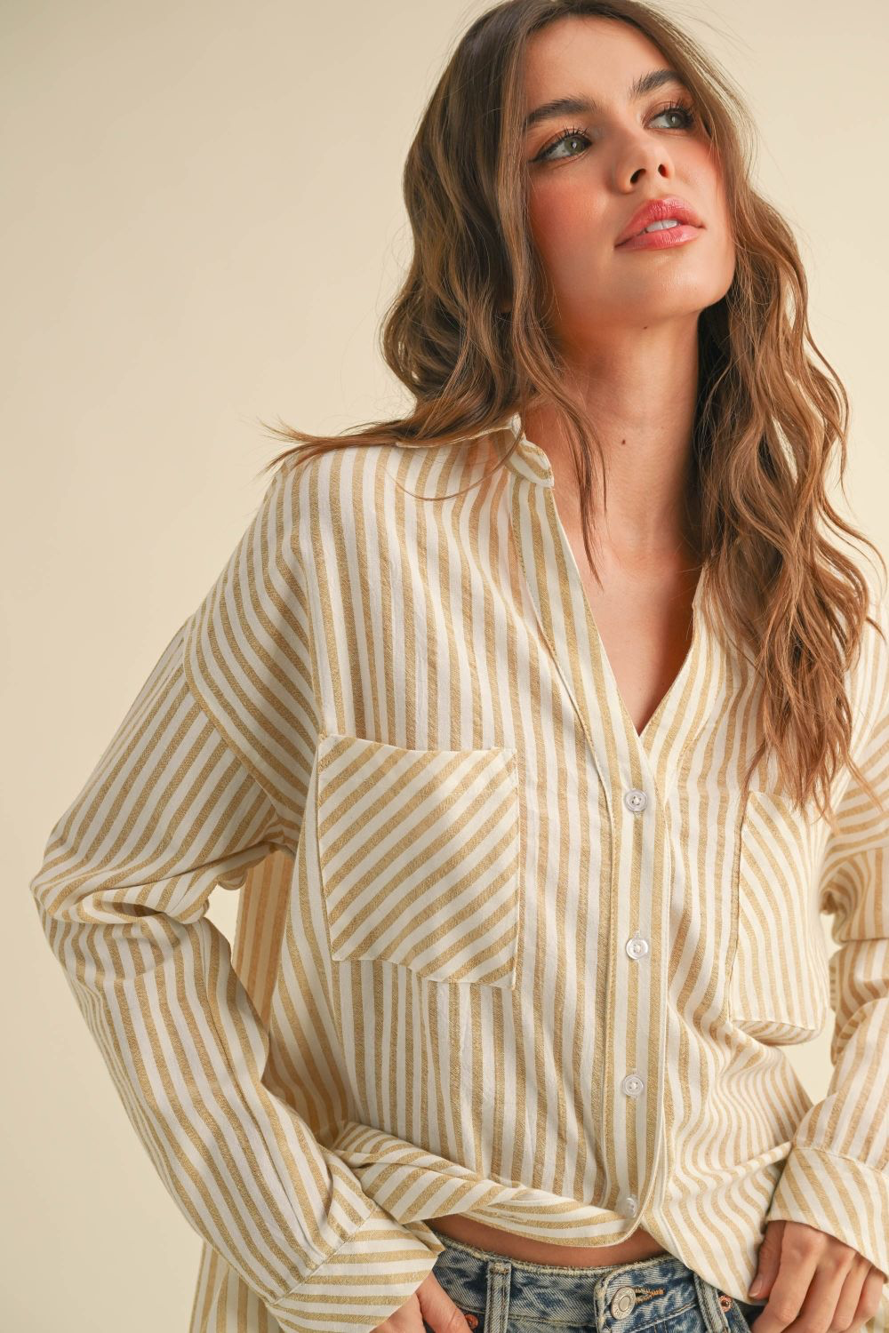 Woman wearing a beige and white striped shirt against a beige background