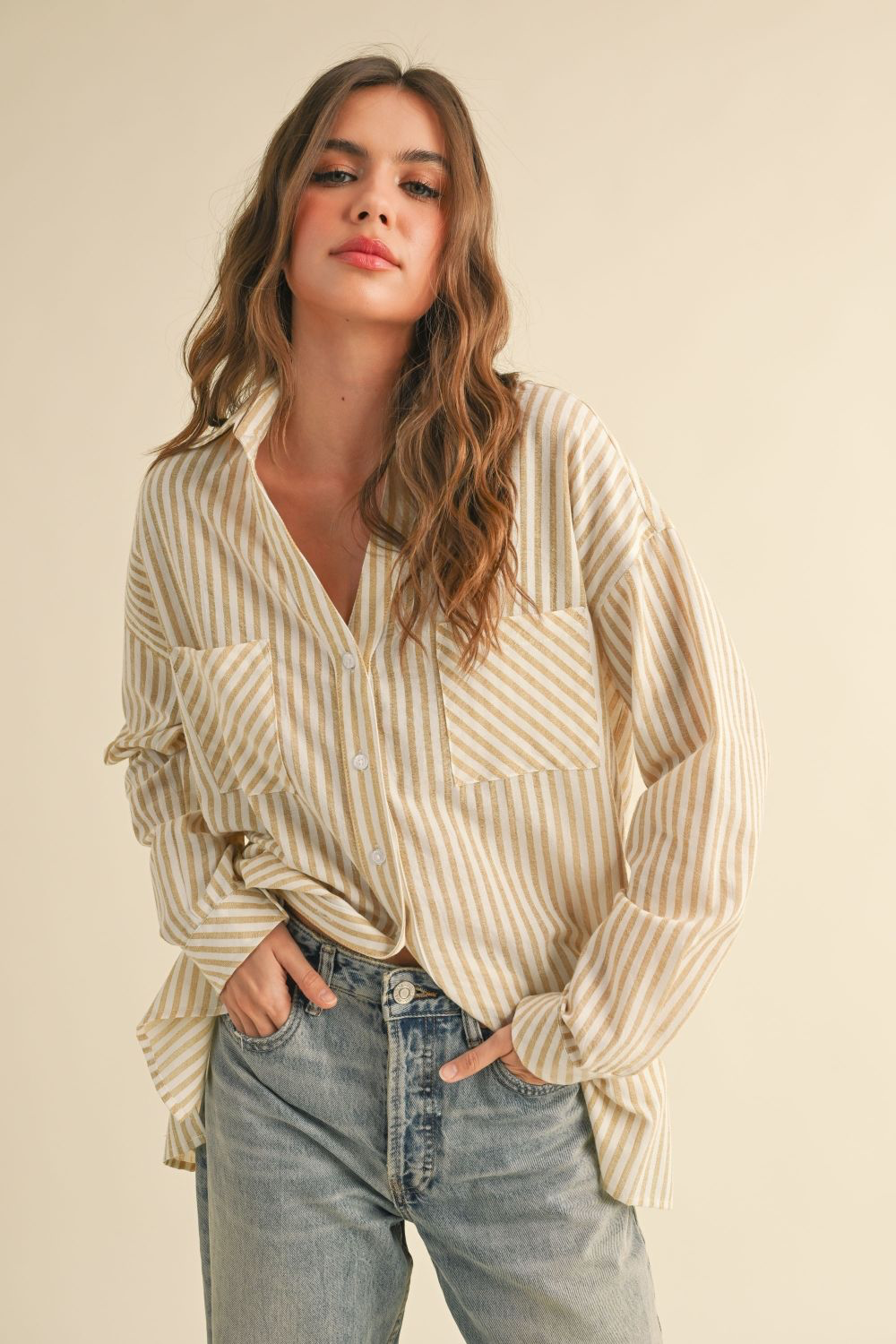 Woman wearing a striped shirt and jeans against a beige background
