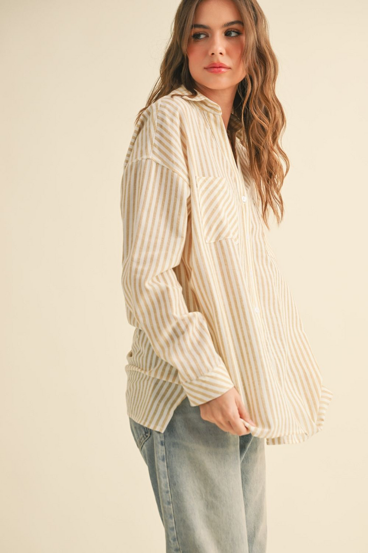 Woman wearing a cream ribbed sweater and light blue jeans on a beige background
