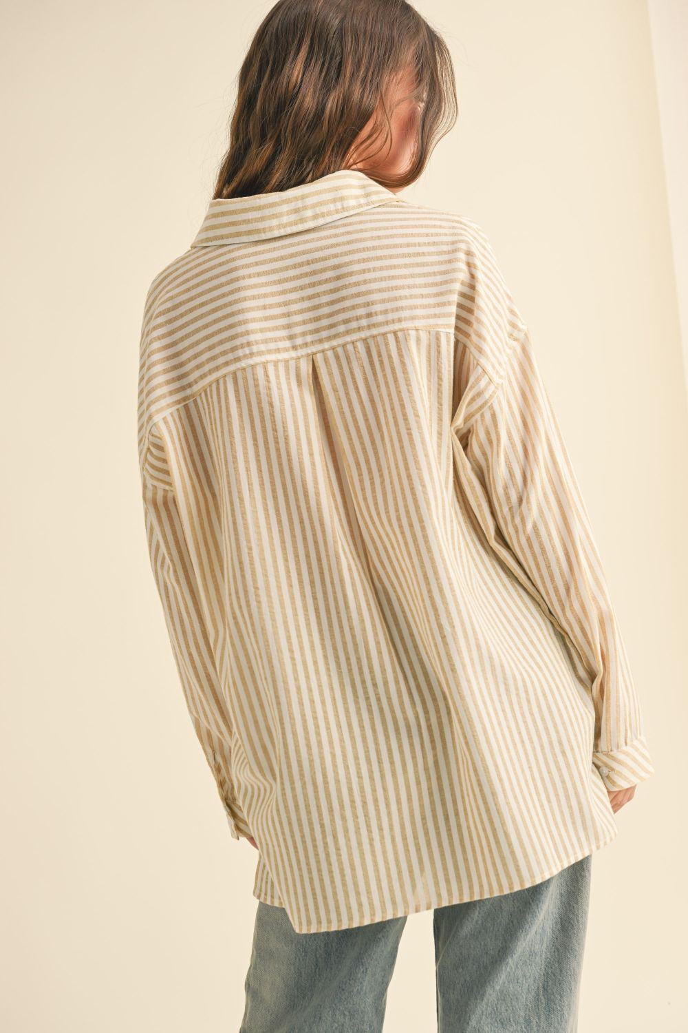 Person wearing a beige and white striped shirt against a beige background