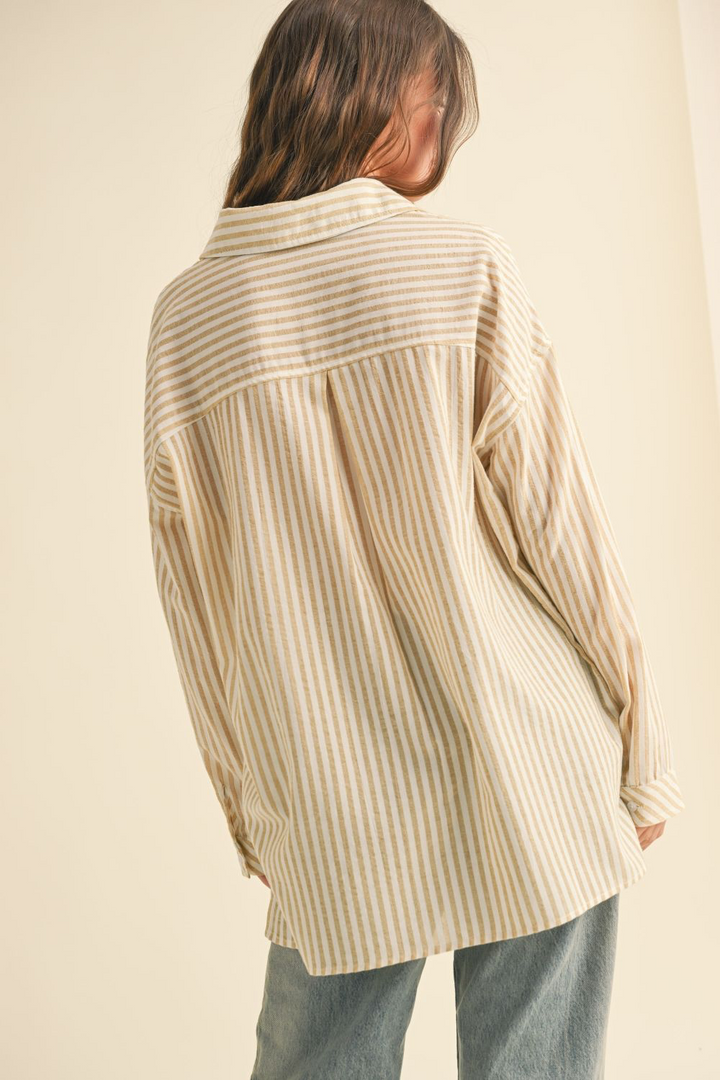 Person wearing a beige and white striped shirt against a beige background