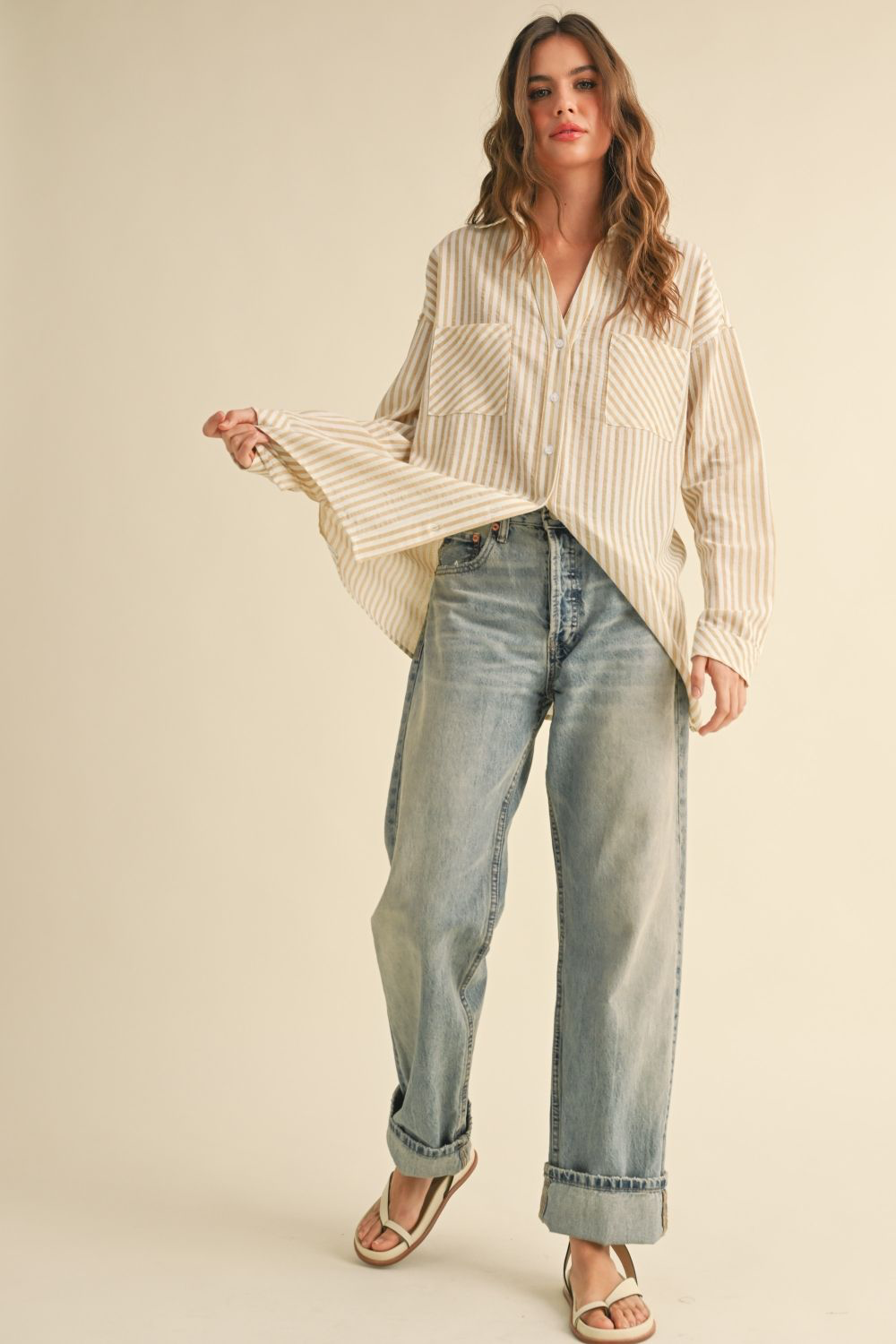 Woman wearing a striped shirt and jeans on a beige background