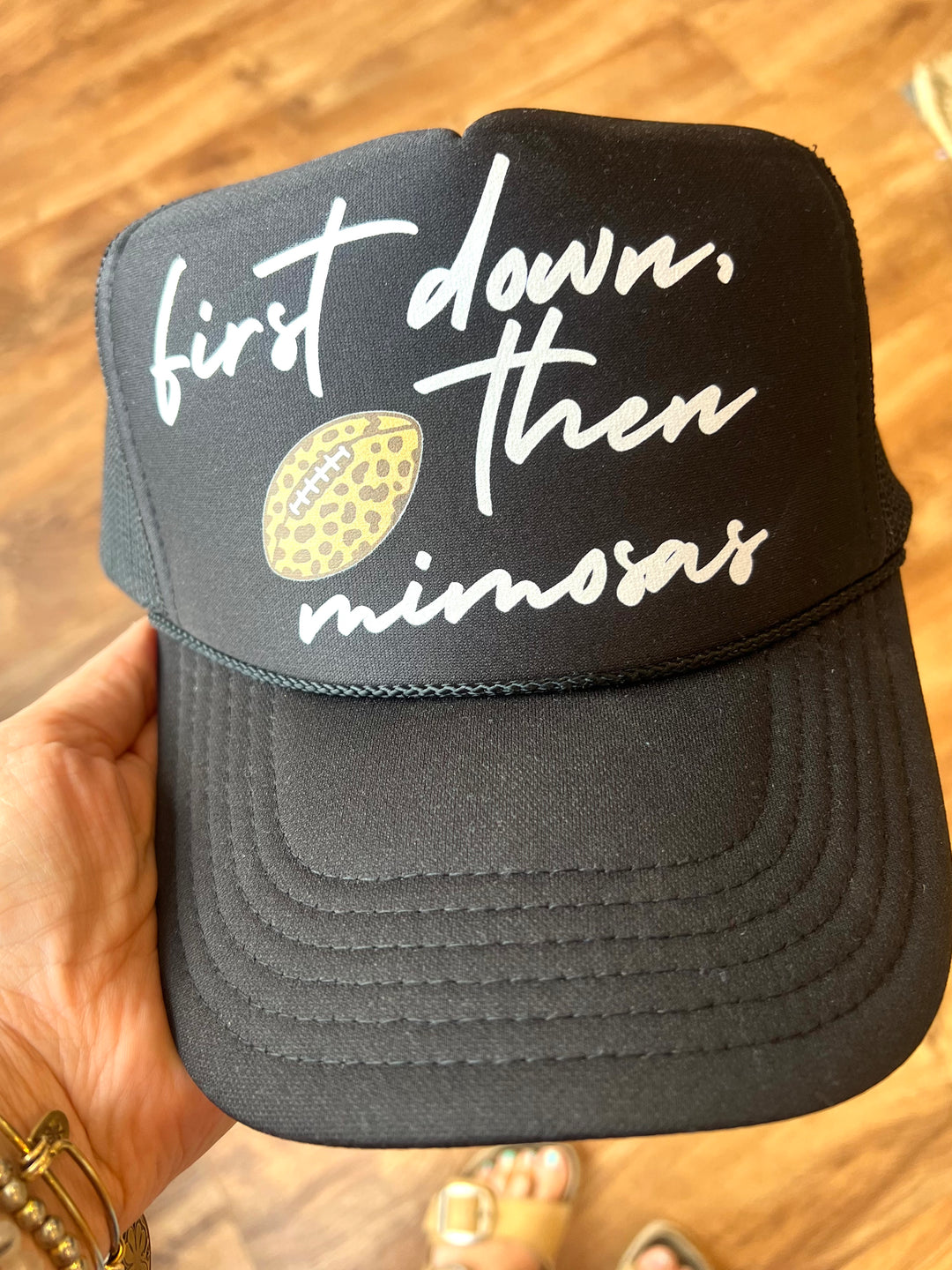 Black cap with white text and a yellow football graphic on a wooden surface