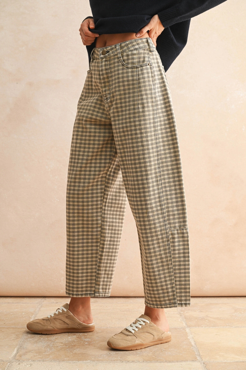 Person wearing plaid pants and brown shoes on a beige background